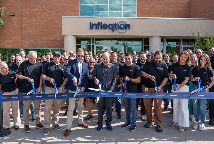 Infleqtion employees cut the ribbon at a grand opening ceremony in front of an Infleqtion office building.