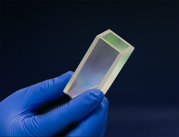 a gloved hand holds a rectangular glass prism