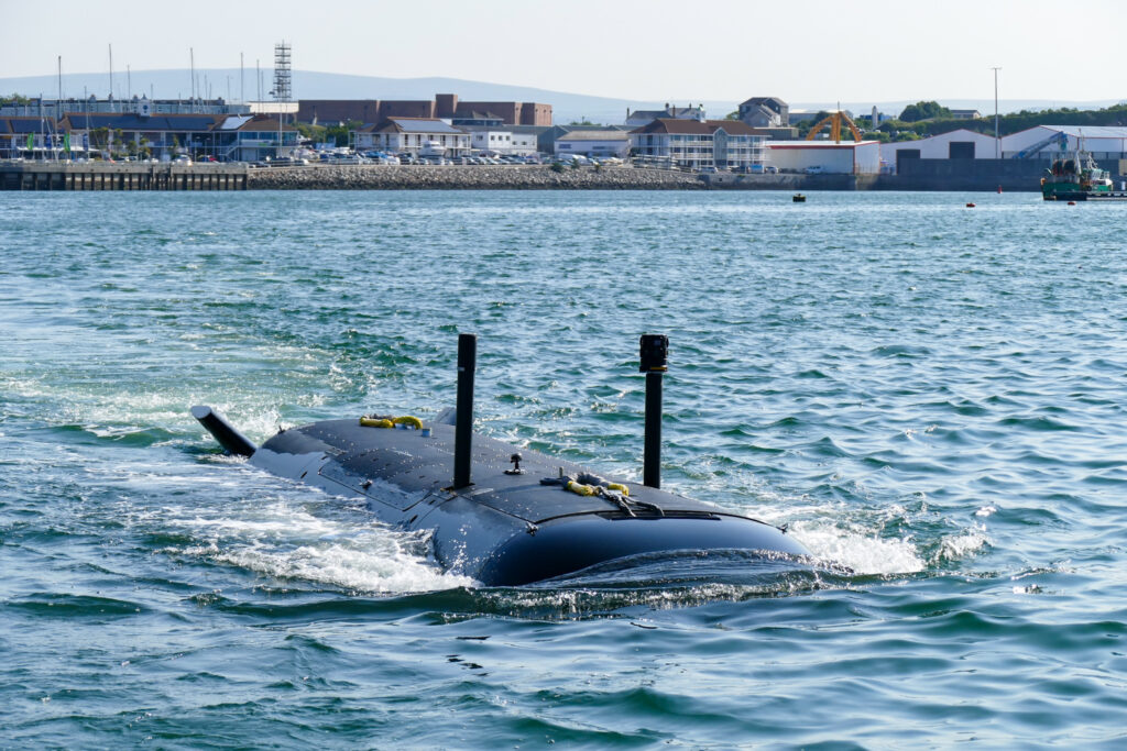A submarine skims the water's surface in a harbor.